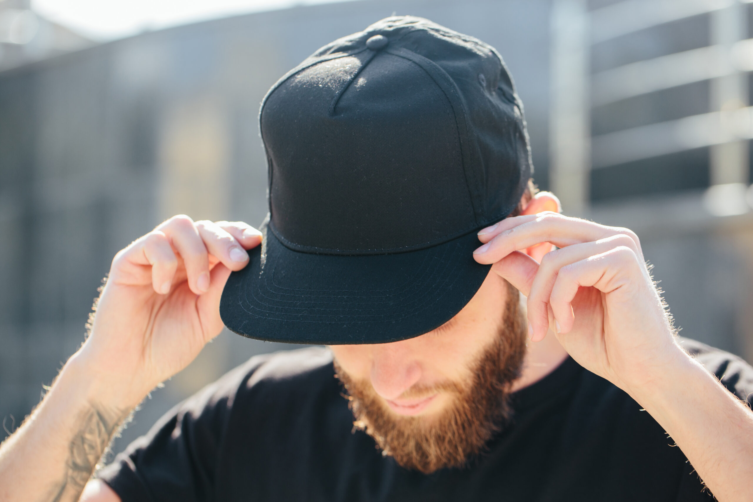 Man placing a black baseball cap on his head.